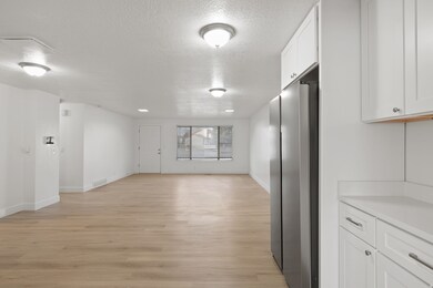 Interior space featuring white cabinetry, a textured ceiling, light wood finished floors, freestanding refrigerator, and open floor plan