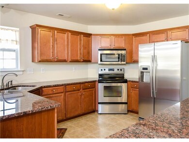 The kitchen has vinyl flooring, wood cabinetry, gr