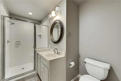 Bathroom featuring tile patterned floors, a shower with door, vanity, and toilet