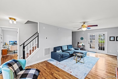Living room with visible vents, ceiling fan, wood
