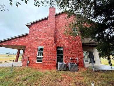 View of side of home with a patio area, a chimney, a balcony, and brick siding