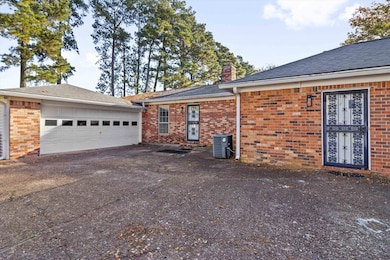 View of side of property featuring a chimney, brick siding, driveway, and roof with shingles