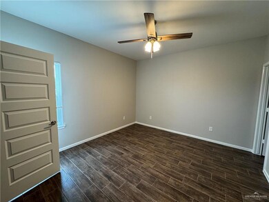 Empty room featuring ceiling fan, dark wood finished floors, and baseboards