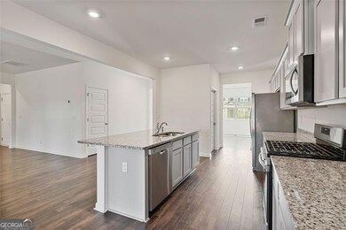 Open-concept kitchen with wide-plank hardwood floors throughout, a massive island and extensive counter space.
