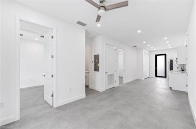 Unfurnished living room with a ceiling fan, recessed lighting, electric panel, and concrete floors