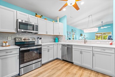 Kitchen with a ceiling fan, appliances with stainless steel finishes, backsplash, vaulted ceiling, and light wood-type flooring