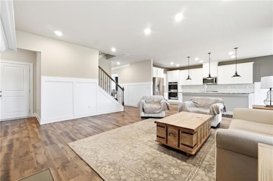Living area featuring stairway, a wainscoted wall, a decorative wall, light wood-style flooring, and recessed lighting
