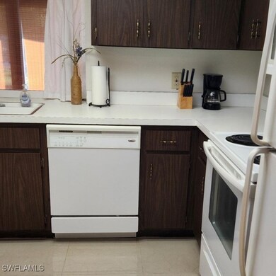Kitchen featuring dark brown cabinets, white appli