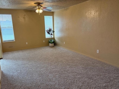 Empty room with a textured ceiling, ceiling fan, a textured wall, carpet, and baseboards