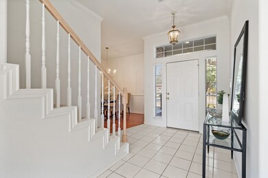 Entryway with a chandelier, crown molding, light tile patterned flooring, and stairs