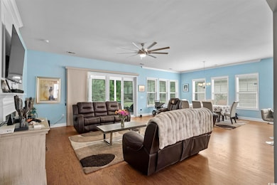 Living area featuring a ceiling fan, wood finished floors, a chandelier, and a fireplace