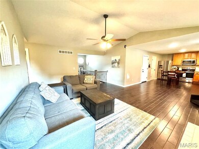 Living room featuring dark wood-style flooring, a ceiling fan, and lofted ceiling