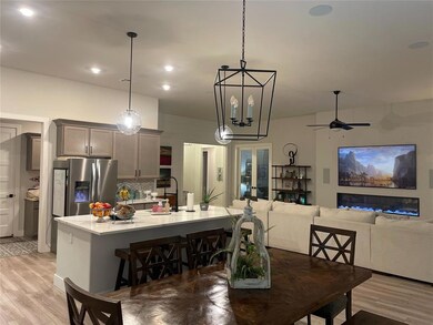 Dining room with ceiling fan with notable chandelier, light hardwood / wood-style flooring, and sink