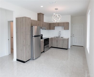 Kitchen featuring freestanding refrigerator, electric stove, under cabinet range hood, light countertops, and a chandelier