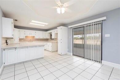 Kitchen featuring a peninsula, a sink, baseboards, light countertops, and a ceiling fan