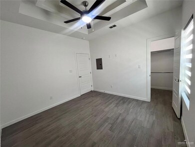 Unfurnished bedroom with dark hardwood / wood-style floors, ceiling fan, electric panel, and a tray ceiling