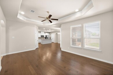 Living room featuring ceiling fan, a tray ceiling,