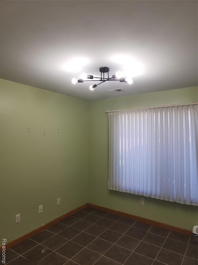Empty room featuring dark tile patterned floors and baseboards