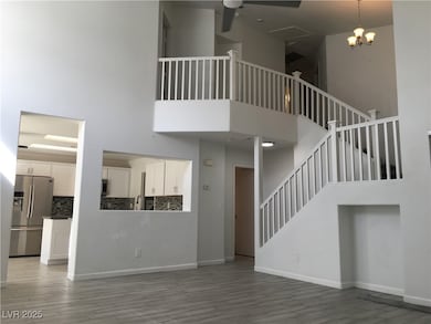 Unfurnished living room with a towering ceiling, light wood-style floors, stairs, and a chandelier