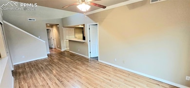 Unfurnished living room featuring ceiling fan, wood finished floors, baseboards, stairway, and ornamental molding