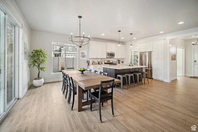 Dining area with a chandelier, light wood-style flooring, and recessed lighting