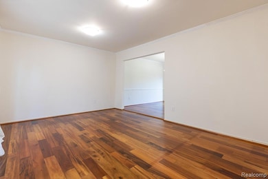 Spare room with ornamental molding and wood-type flooring
