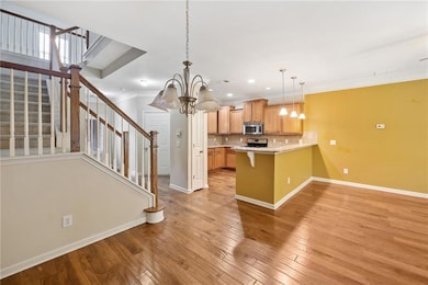 Kitchen featuring stainless steel appliances, a chandelier, baseboards, a peninsula, and a breakfast bar area