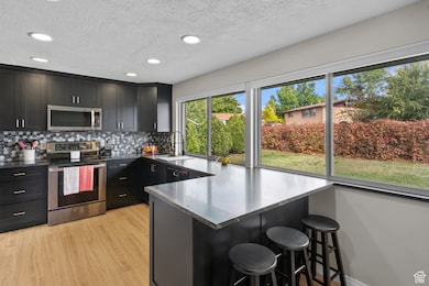 Kitchen with appliances with stainless steel finishes, recessed lighting, a breakfast bar area, a textured ceiling, and a peninsula