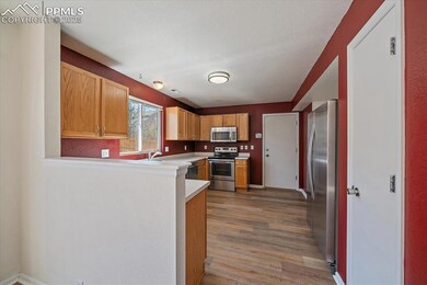 Kitchen with light wood-type flooring, appliances with stainless steel finishes, light countertops, and a peninsula