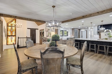 Dining room featuring a chandelier, light wood-style flooring, a wood ceiling with exposed beams, and recessed lighting
