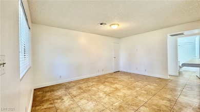 Unfurnished room with a textured ceiling, light ti