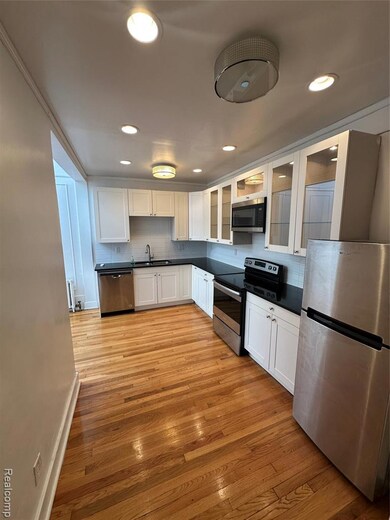 Kitchen with appliances with stainless steel finishes, white cabinets, glass insert cabinets, decorative backsplash, and recessed lighting