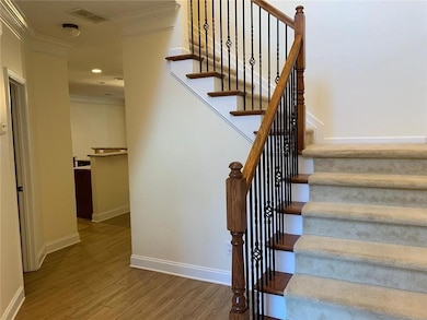 Stairway featuring crown molding, visible vents, wood finished floors, and baseboards