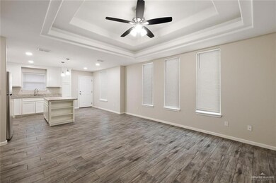 Unfurnished living room featuring a raised ceiling, dark wood-style floors, ceiling fan, baseboards, and recessed lighting