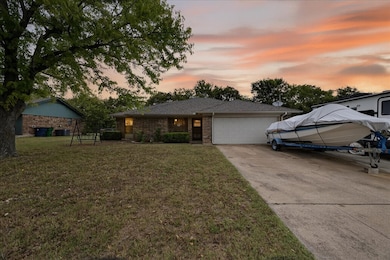 Ranch-style home featuring a front lawn, driveway, an attached garage, and brick siding