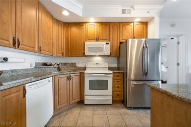 Kitchen featuring white appliances, ornamental molding, stone countertops, and sink