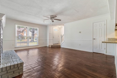 Unfurnished living room featuring a textured ceiling, wood finished floors, ceiling fan, ornamental molding, and stairs