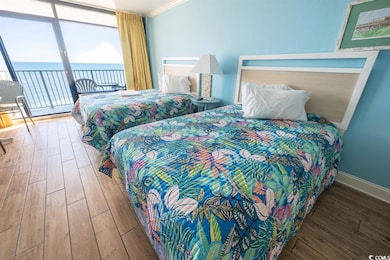 Bedroom featuring access to outside, floor to ceiling windows, wood finished floors, a water view, and crown molding