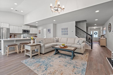 Living room featuring stairway, a chandelier, light wood finished floors, high vaulted ceiling, and recessed lighting