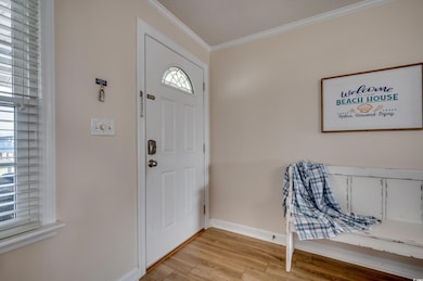 Foyer featuring crown molding, light wood-type flooring, and baseboards