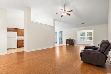 Living room with a ceiling fan, light wood-style floors, and high vaulted ceiling