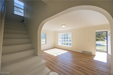Staircase featuring arched walkways and wood finished floors