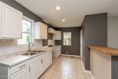 Updated Kitchen featuring light tile patterned floors, white cabinetry, wooden counters, recessed lighting, and tasteful backsplash