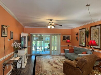 Living room with wood finished floors, a ceiling fan, crown molding, and baseboards