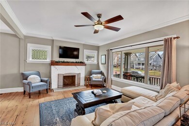 Living room with light hardwood / wood-style flooring, crown molding, a fireplace, and ceiling fan