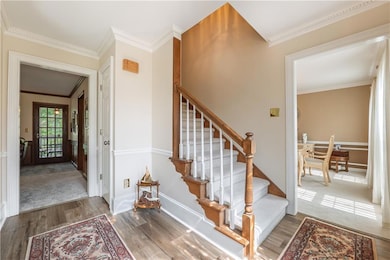 Staircase with wood finished floors, crown molding, and baseboards