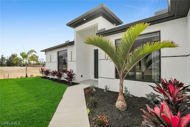 View of exterior entry featuring a yard and stucco