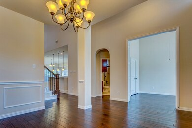Unfurnished room featuring a chandelier, dark wood-style floors, arched walkways, and stairs