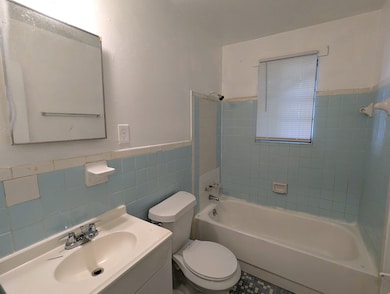 Full bathroom with toilet, a wainscoted wall, bathing tub / shower combination, tile walls, and vanity