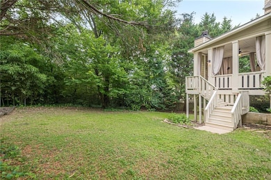 Rear view of property featuring a covered porch with an outdoor stone fireplace. The view of the fireplace is a focal point from inside the kitchen, breakfast area, dining and Family room.